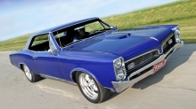 Синий Pontiac GTO разгоняется на прямой дороге с отличной видимостью